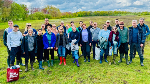 Group photo of LSB team members standing in a lush green field during a volunteer event