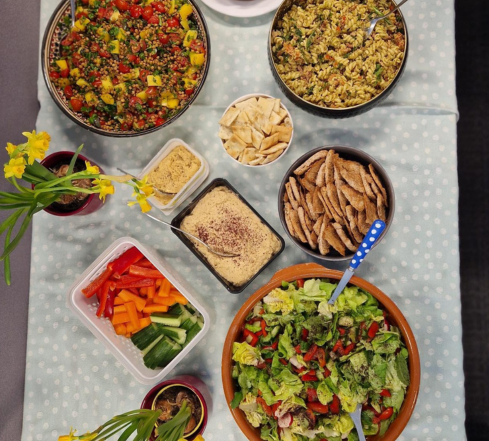 Aerial view of table filled with delicious food - veggies, hummus, salads and more