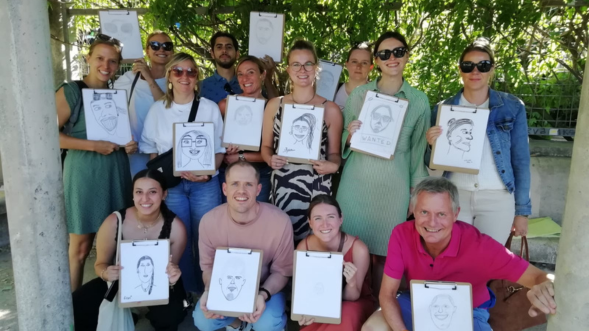 Group photo of Sales team with drawings on clipboards of themselves