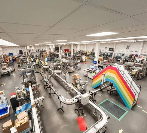 Manufacturing facility floor with machinery and bridge with rainbow graphic on the side