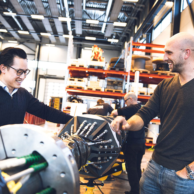 Two people smiling and talking next to a subsea tool
