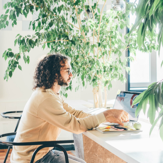 Man with curly hair and glasses working on a computer