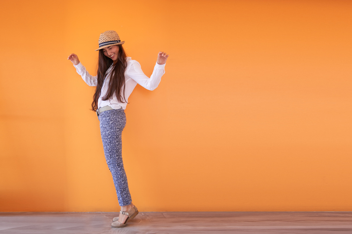 Cheerful  girl standing against orange background