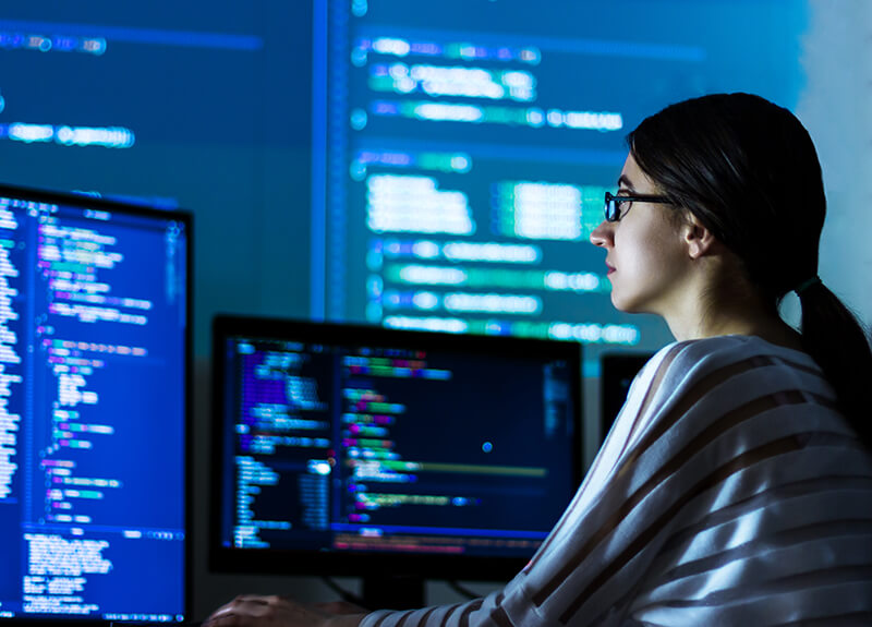 Woman sitting in front of several computer monitors