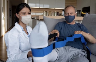 Nurse helping patient with physical therapy at home