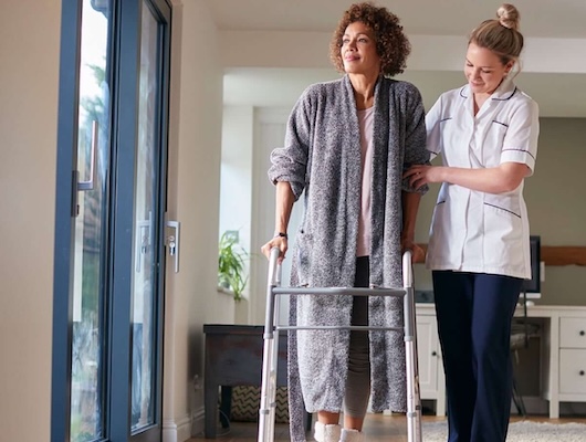 Home health nurse helping a woman walk
