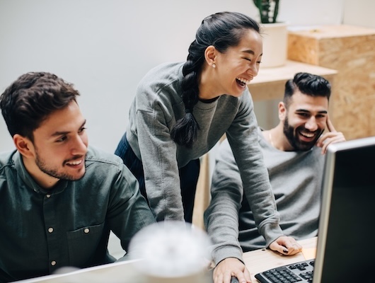 Three colleagues laughing at work