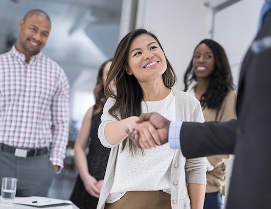 Colleagues shaking hands with a group behind