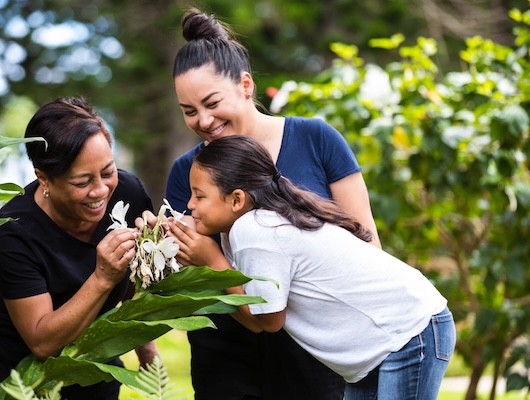 Grandmother, mom and daughter smelling flowers
