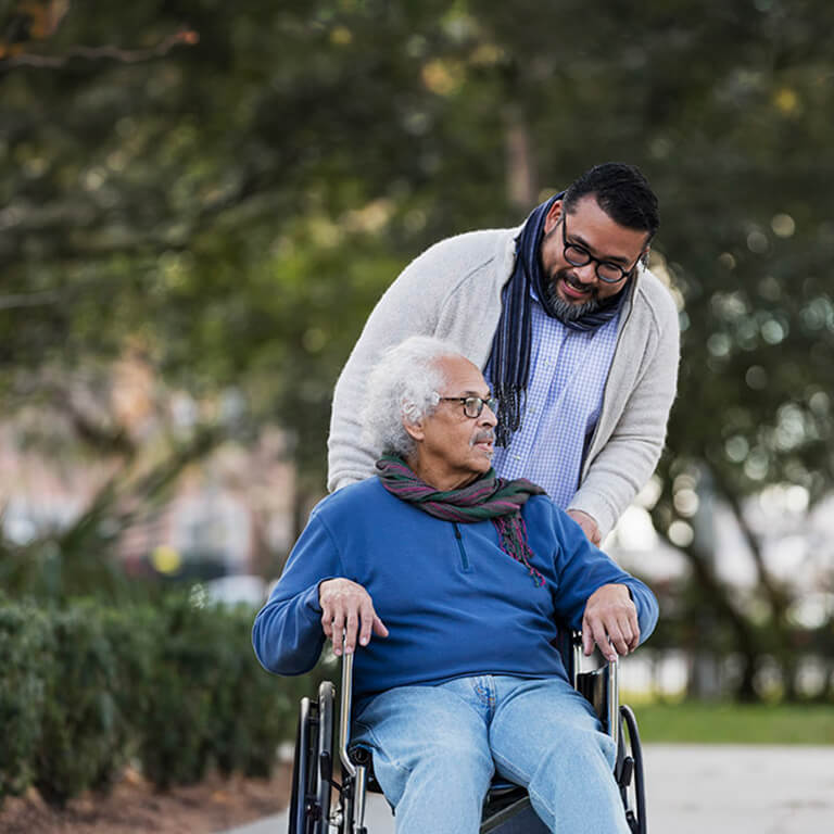Man pushing an elderly person in a wheelchair