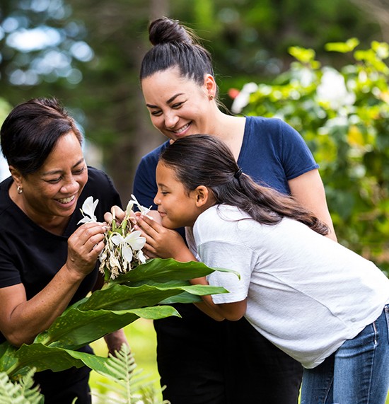 Grandmother, mom and daughter smelling flowers