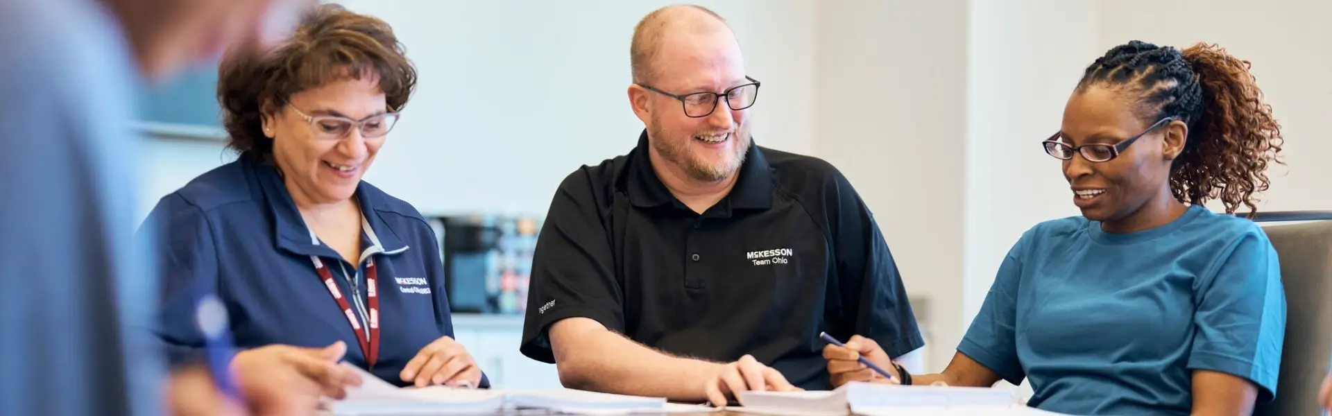 three McKesson employees sitting at a table working and smiling