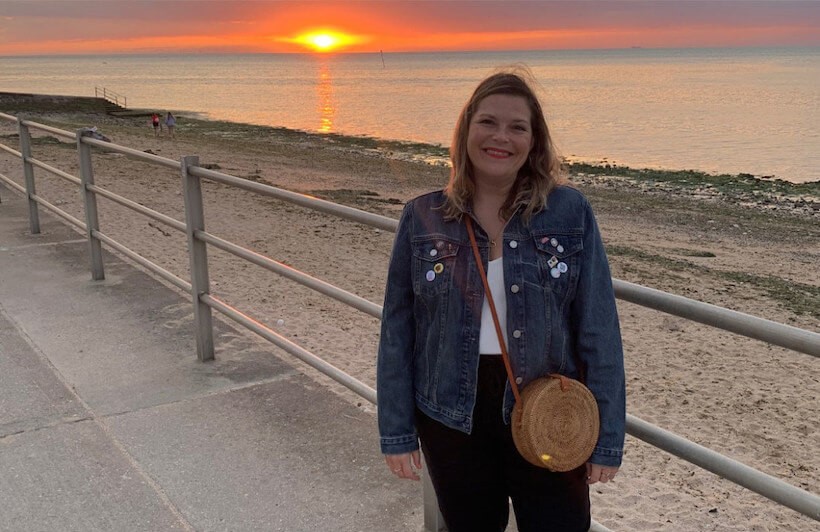 Audible employee smiling on the beach during sunset