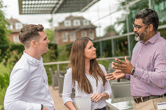 Three employees talking in an outdoor office area