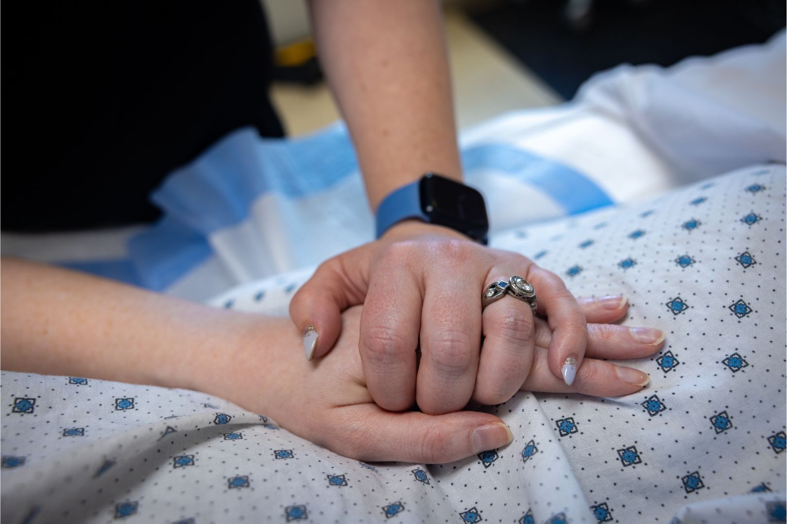 Patient holding a nurse's hand