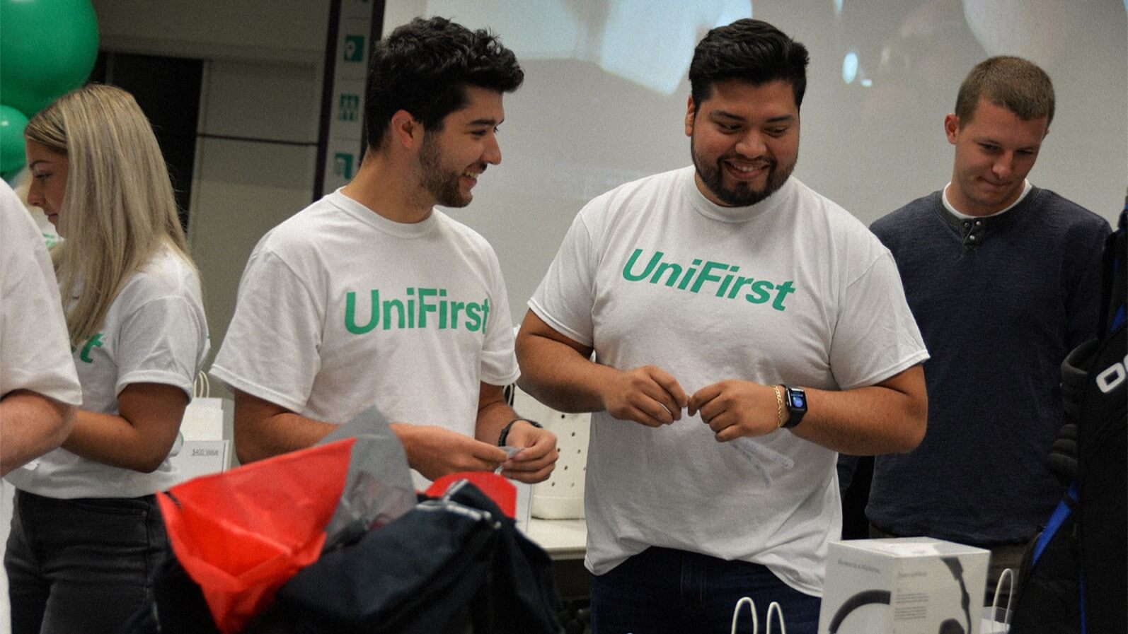 Several people are standing together while wearing UniFirst t-shirts.