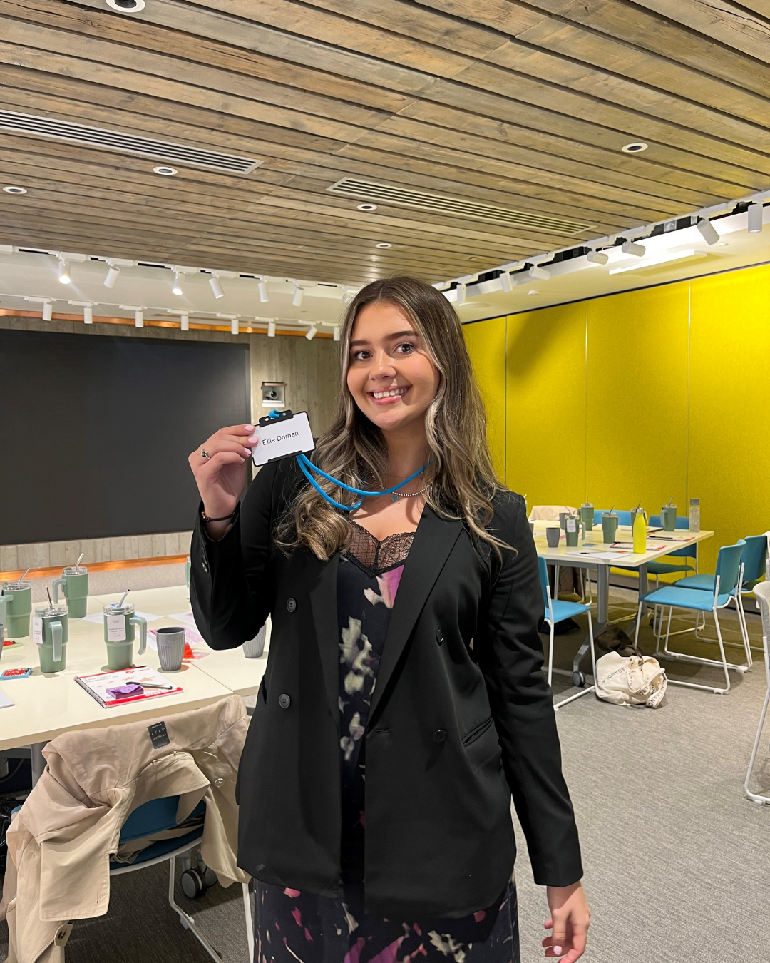 Colleague standing in meeting room smiling and holding their name badge