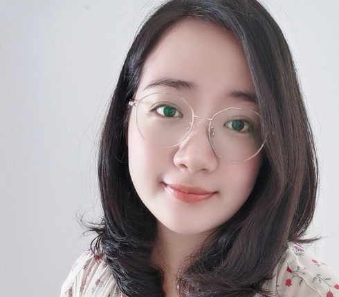 Iris, a Chinese woman, with shoulder length dark hair, wide light metal framed glasses, wearing a pale floral printed blouse.