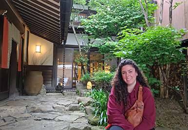 Andrea in a traditional Japanese garden courtyard with stone path and lush green plants.