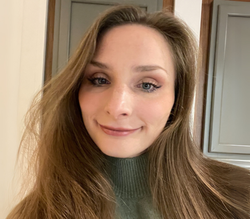 Katherine, white female, with long redish-brown hair with blue eyes wearing a green tutrleneck sweater