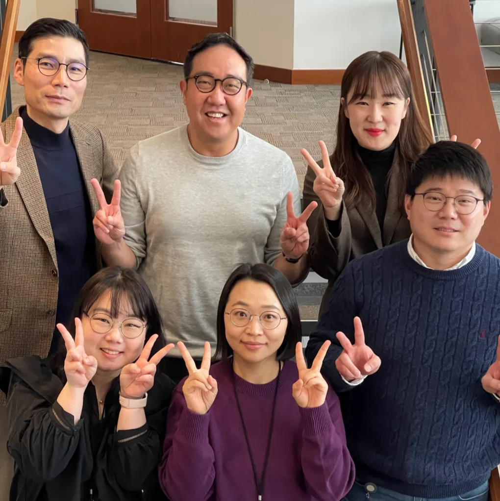 Group of people smiling for the camera displaying peace signs with their hands