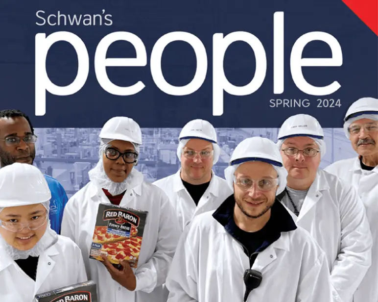 Employees smiling for the camera wearing lab coats and hard hats