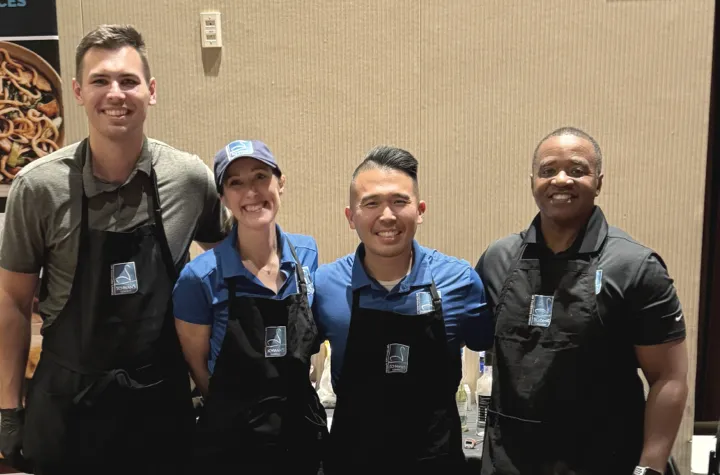 Four people wearing aprons smiling for the camera