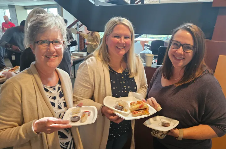 Three women smiling for the camera having appetizers