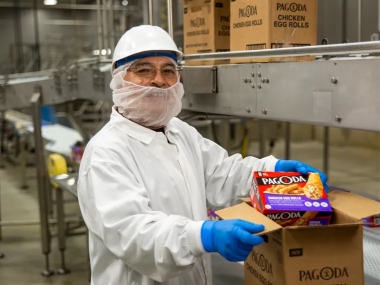 Man working in food production wearing a labcoat and gloves