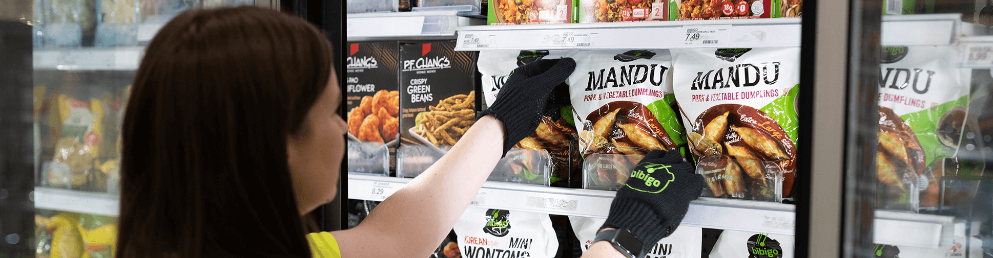 Woman employee stocking shelves while wearing gloves