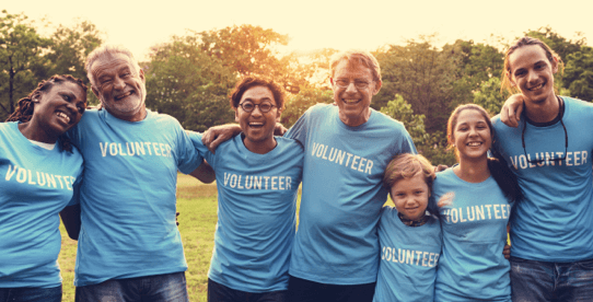 Group of people smiling and wearing volunteer t-shirts