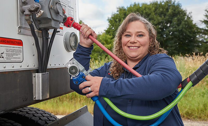 driver smiling while connecting brake lines on a truck