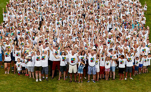 Dozens of Quad employees in a field at an outdoor event, cheering