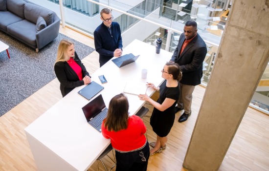 A group of employees standing around a table and conversing.