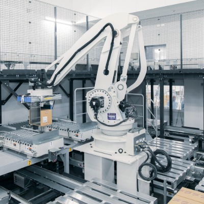 A robot arm moving a box to a conveyor belt