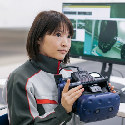 a woman sitting in front of a computer holding a VR headpiece