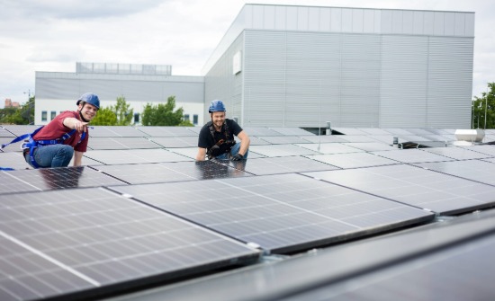 2 male GSQ employees on a building rooftop working on solar panels