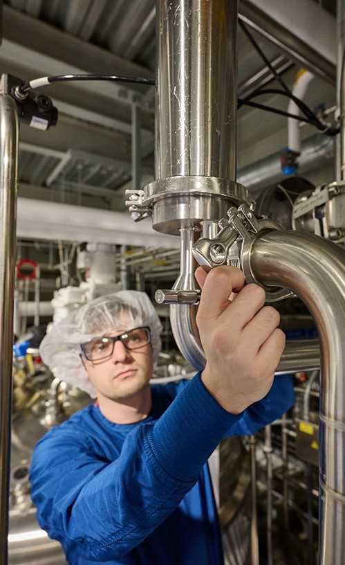 worker adjusting a pipe in a factory