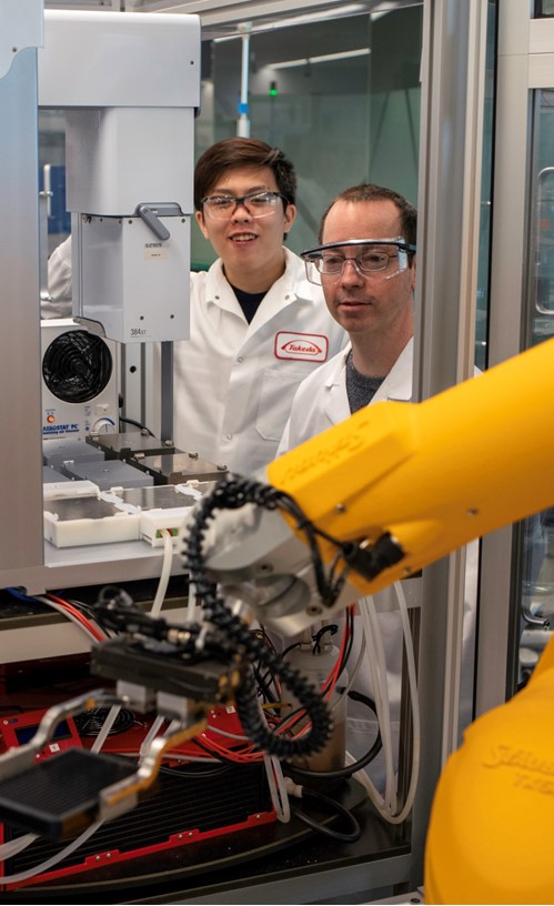 two people in lab coats operating robot machinery