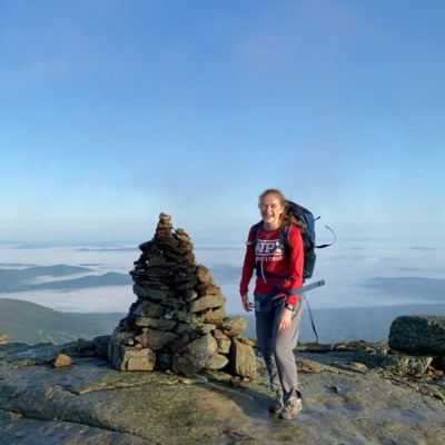 Female standing on top of a mountain with a red sweater and backpack