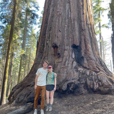 2 people standing in front of a large tree