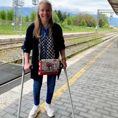 Female at a train station platform wearing a black jacket with crutches