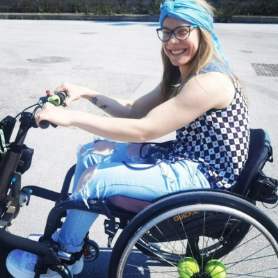 Female in a wheelchair with a blue headband smiling