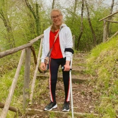 Female on a forest path with crutches wearing a red top