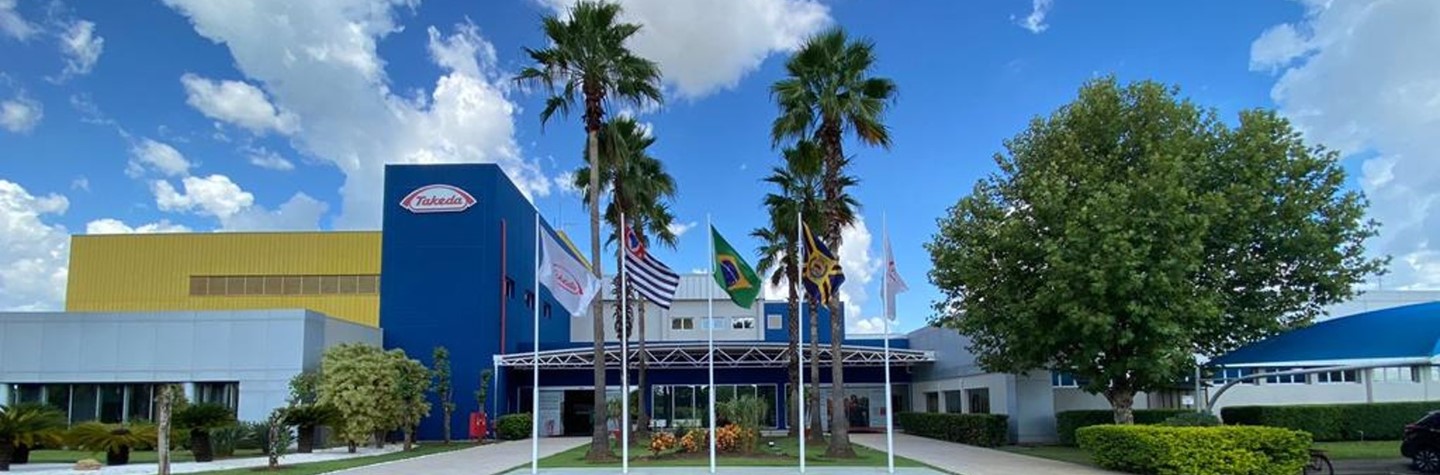 front view of Takeda facility with trees and flags