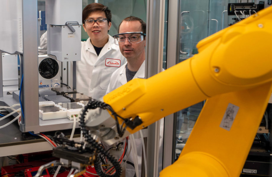 employees looking at a robot working on products