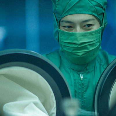Person in sterile garb and facemask working in a lab