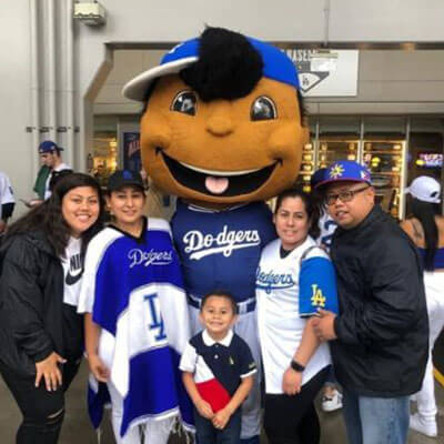 Rosa and her family posing with the Dodgers Mascot at the baseball stadium