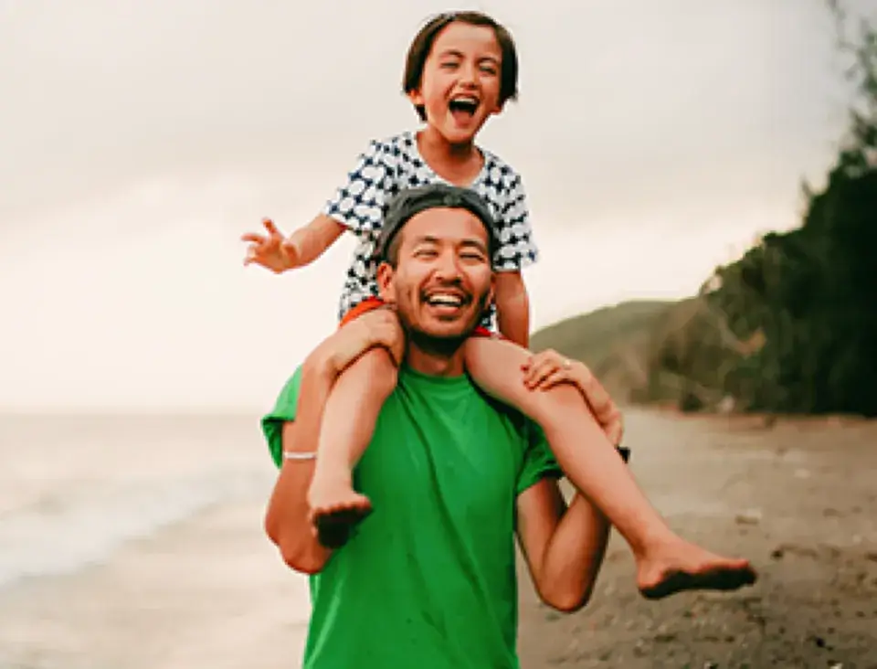 happy father carrying his child on his shoulders at the beach