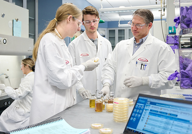 employees in lab coats carefully handling lab equipment